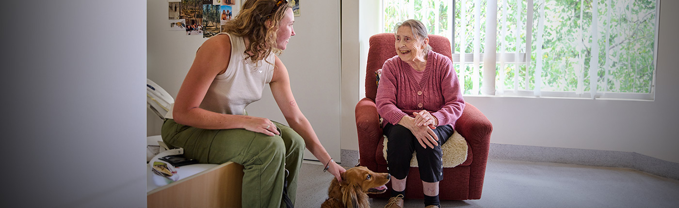 resident and care worker patting dog